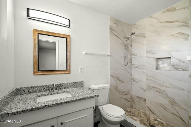 bathroom with vanity, tiled shower, and toilet