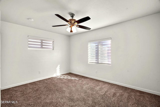 empty room featuring dark colored carpet, plenty of natural light, and ceiling fan