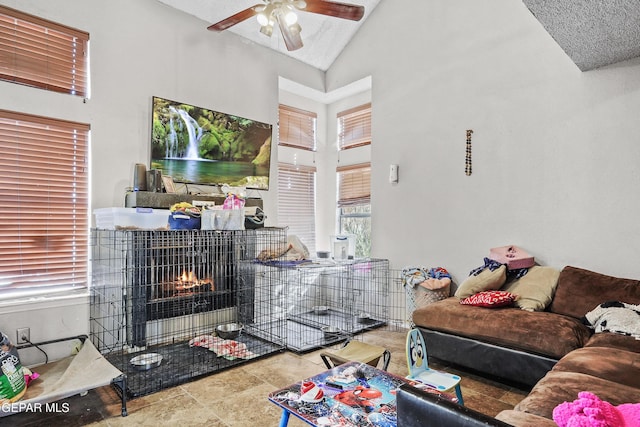 living room featuring a tile fireplace, ceiling fan, and high vaulted ceiling