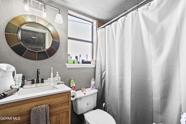 bathroom with vanity, curtained shower, toilet, and a textured ceiling