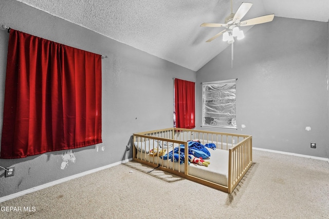 unfurnished bedroom with vaulted ceiling, a textured ceiling, ceiling fan, carpet, and a crib