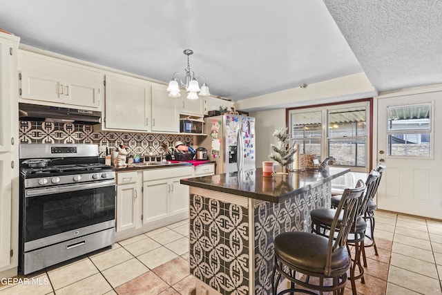 kitchen with stainless steel appliances, hanging light fixtures, a breakfast bar area, and light tile patterned floors