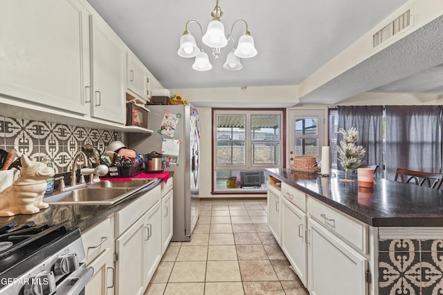 kitchen with pendant lighting, sink, light tile patterned floors, white cabinetry, and stainless steel appliances