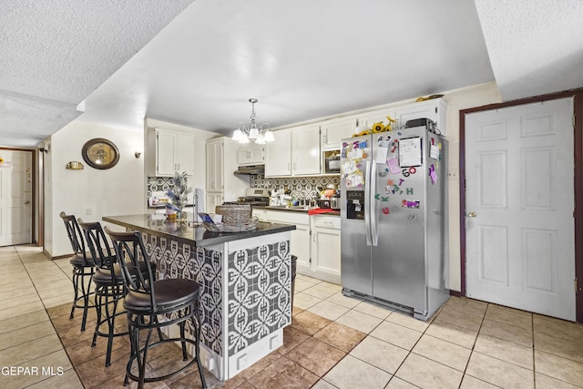 kitchen featuring light tile patterned floors, a breakfast bar area, stainless steel appliances, and white cabinets