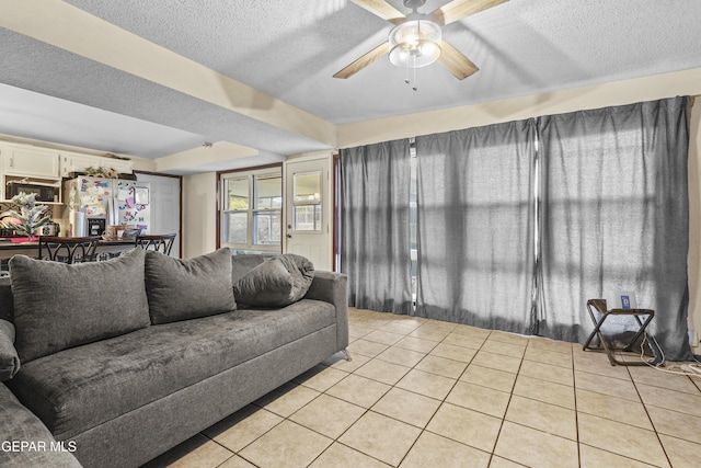 living room featuring ceiling fan, a textured ceiling, and light tile patterned floors