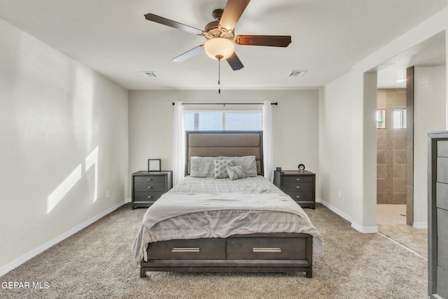 carpeted bedroom with ceiling fan and ensuite bath