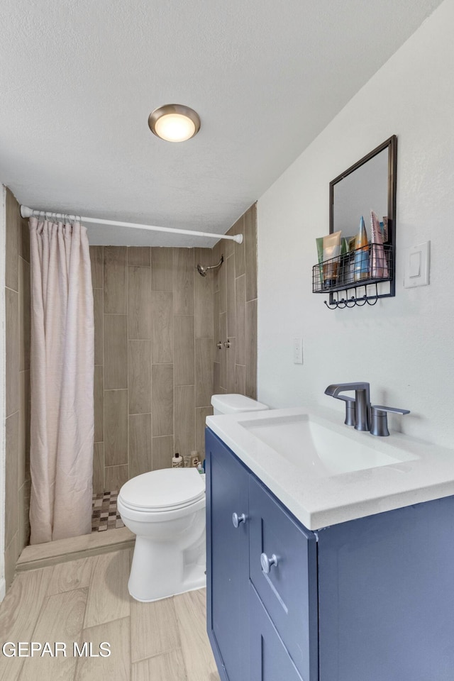 bathroom featuring toilet, vanity, a textured ceiling, and a shower with curtain