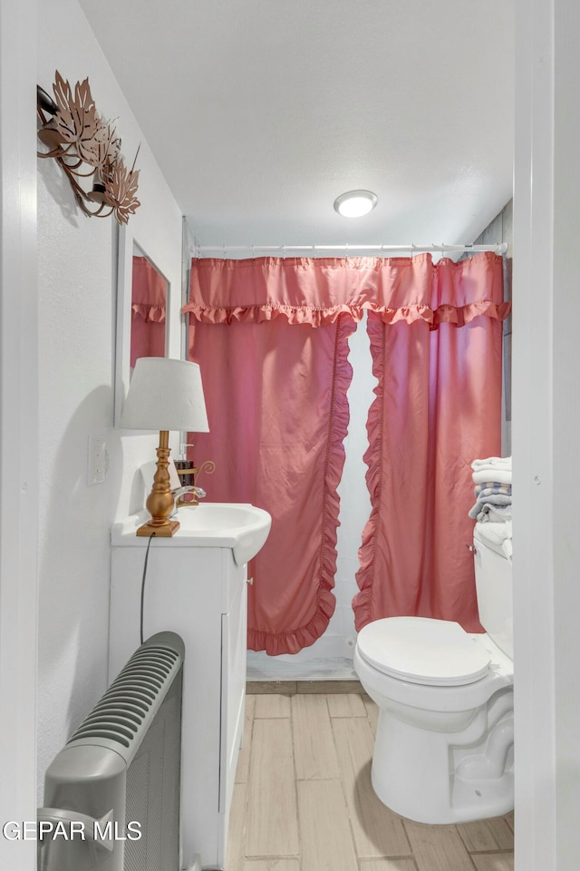 bathroom with vanity, radiator heating unit, and toilet