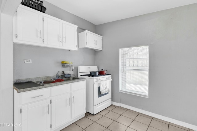 kitchen featuring sink, light tile patterned floors, gas range gas stove, and white cabinets