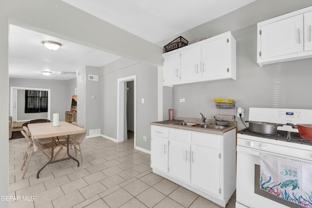 kitchen with white cabinetry, sink, light tile patterned floors, and white gas stove