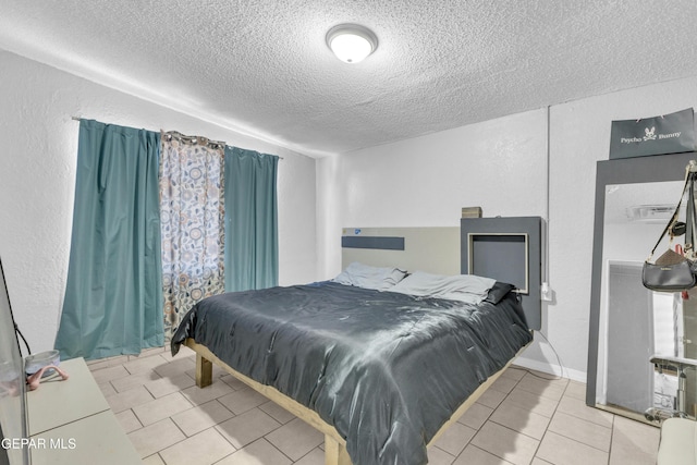 bedroom featuring light tile patterned flooring and a textured ceiling