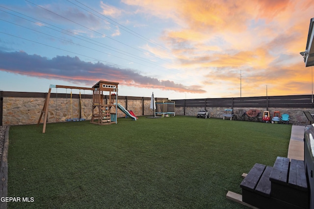 yard at dusk with a playground and a trampoline