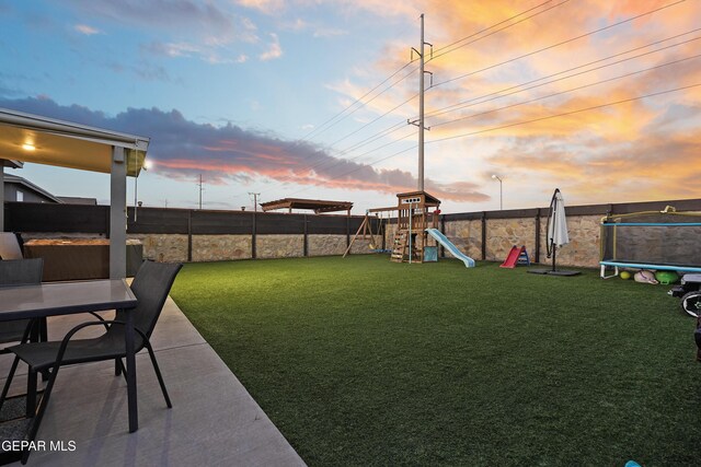 yard at dusk with a patio, a playground, and a trampoline