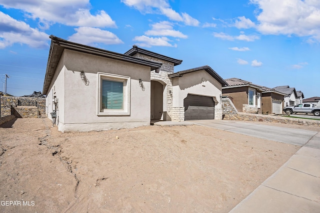 view of front of property with an attached garage, stone siding, concrete driveway, and stucco siding