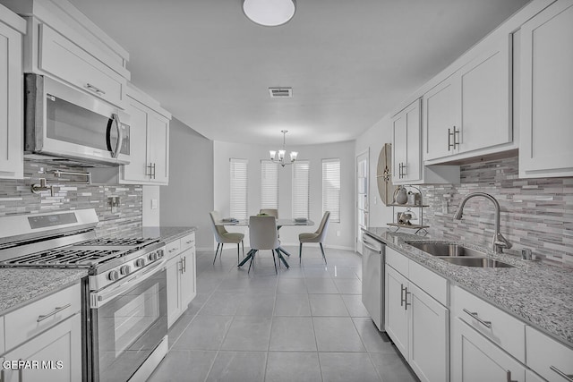 kitchen featuring stainless steel appliances, white cabinetry, light stone countertops, and sink