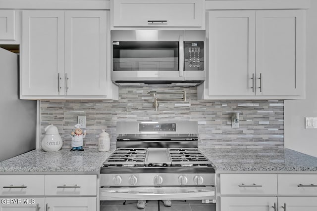 kitchen with light stone countertops, white cabinetry, and appliances with stainless steel finishes