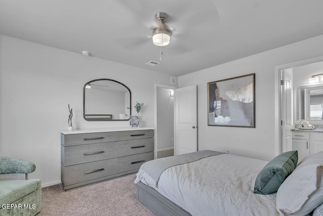 bedroom with ceiling fan, ensuite bathroom, and light carpet