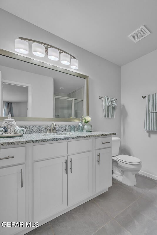 bathroom with a shower with door, vanity, and toilet