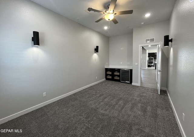 unfurnished living room featuring wine cooler, ceiling fan, and dark colored carpet