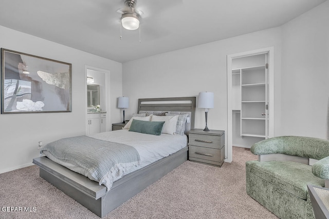 bedroom with connected bathroom, a walk in closet, ceiling fan, light carpet, and a closet