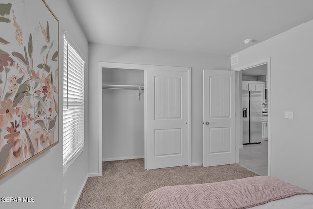 carpeted bedroom featuring stainless steel fridge and a closet