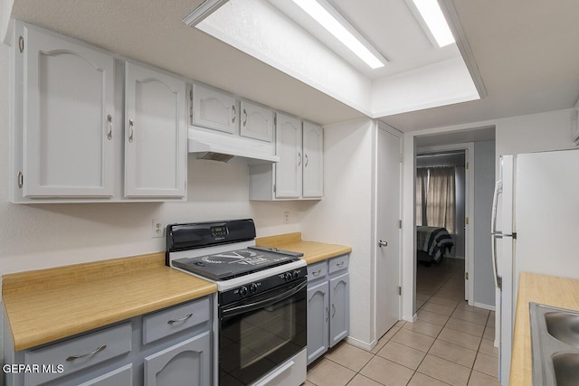 kitchen featuring gray cabinetry, light tile patterned floors, range with gas cooktop, and white refrigerator