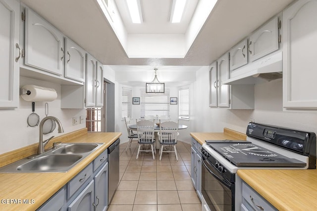 kitchen featuring sink, stainless steel dishwasher, range, light tile patterned floors, and a raised ceiling