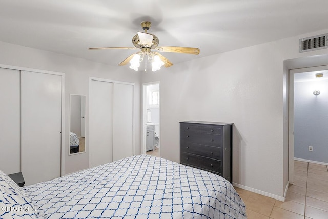 tiled bedroom with ceiling fan and multiple closets