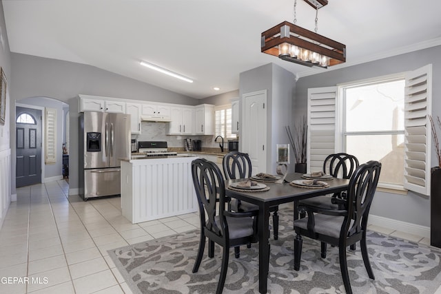 dining area with sink, a chandelier, vaulted ceiling, and light tile patterned floors