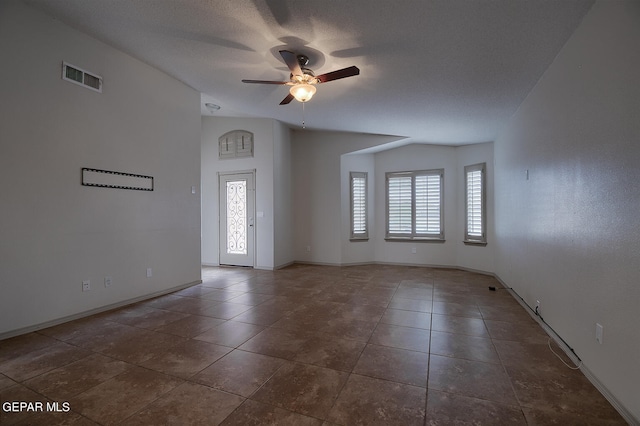 unfurnished room featuring ceiling fan, dark tile patterned flooring, vaulted ceiling, and a textured ceiling