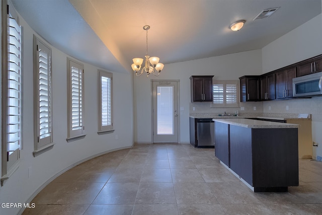 kitchen featuring a kitchen island, appliances with stainless steel finishes, hanging light fixtures, dark brown cabinetry, and an inviting chandelier