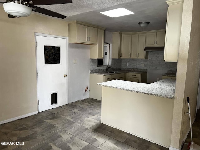 kitchen featuring sink, tasteful backsplash, kitchen peninsula, ceiling fan, and cream cabinets