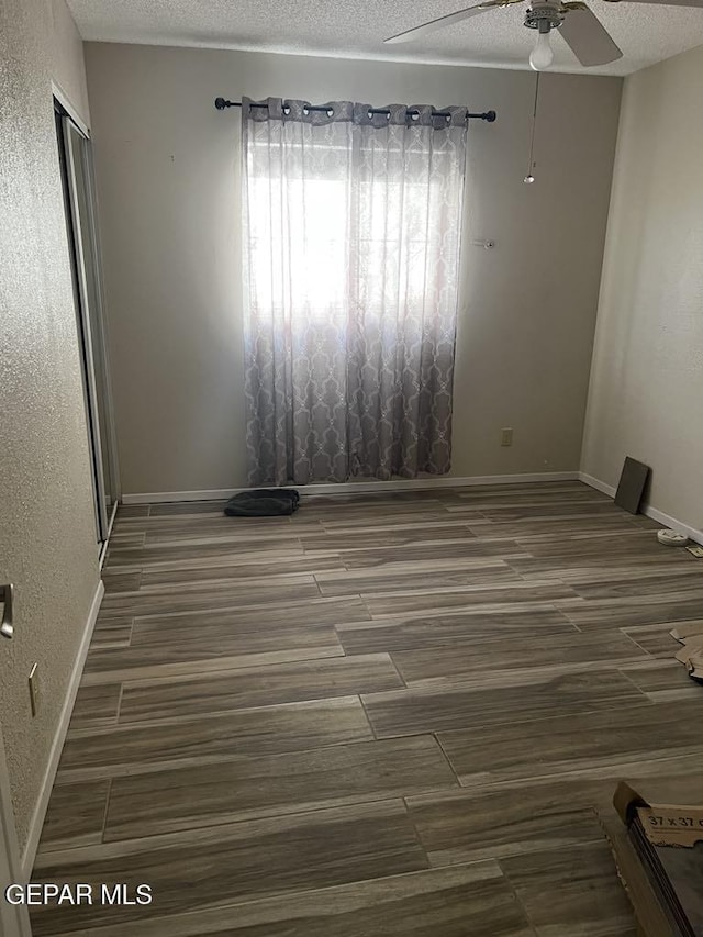 spare room with dark hardwood / wood-style flooring, ceiling fan, and a textured ceiling