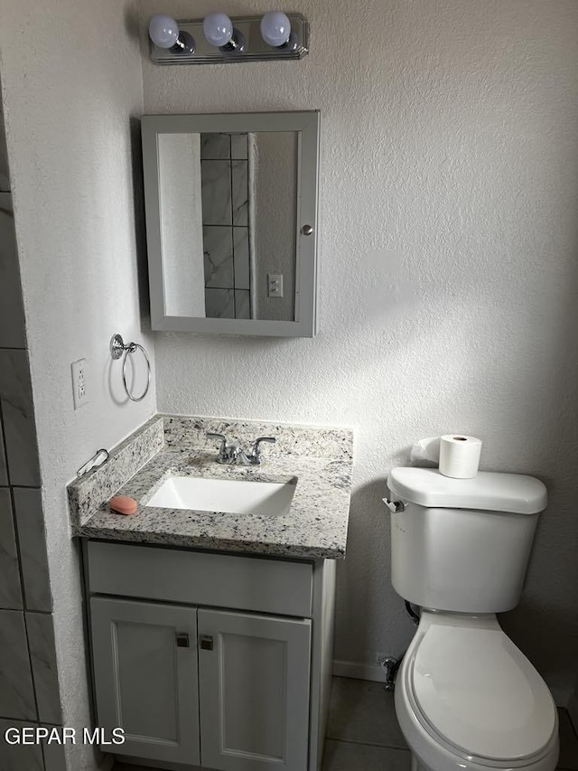 bathroom with tile patterned flooring, vanity, and toilet