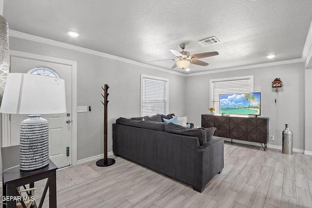 living room with ornamental molding, ceiling fan, a textured ceiling, and light hardwood / wood-style flooring