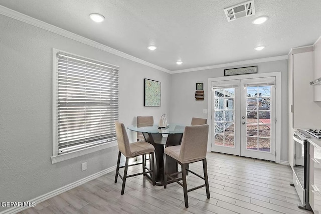 dining room featuring crown molding, a textured ceiling, light wood-type flooring, and french doors