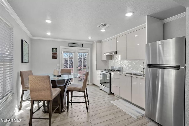 kitchen featuring sink, a breakfast bar area, appliances with stainless steel finishes, white cabinetry, and tasteful backsplash