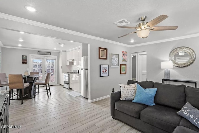 living room featuring ceiling fan, ornamental molding, light hardwood / wood-style floors, and a textured ceiling