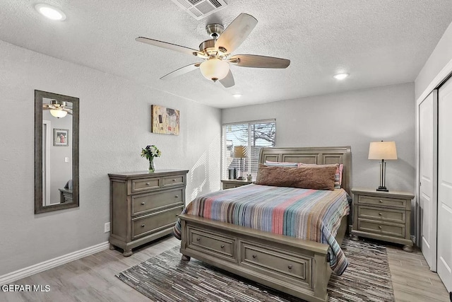 bedroom with a closet, ceiling fan, a textured ceiling, and light hardwood / wood-style flooring