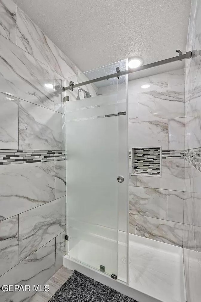 bathroom featuring an enclosed shower and a textured ceiling