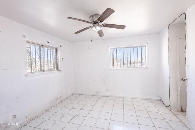 tiled spare room featuring a wealth of natural light and ceiling fan