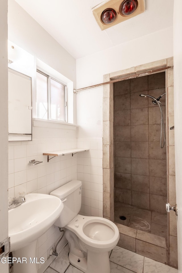 bathroom with tile walls, sink, toilet, and tiled shower