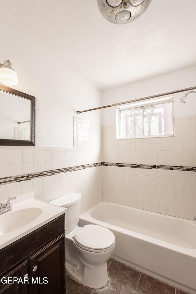 full bathroom with tile patterned floors, toilet, tile walls, vanity, and tiled shower / bath combo