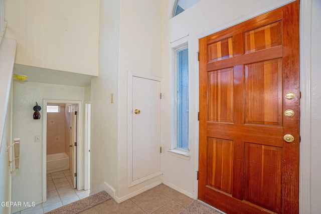 foyer entrance featuring light tile patterned floors and a towering ceiling