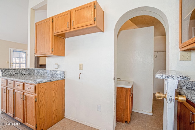 kitchen featuring sink, light tile patterned floors, and light stone countertops