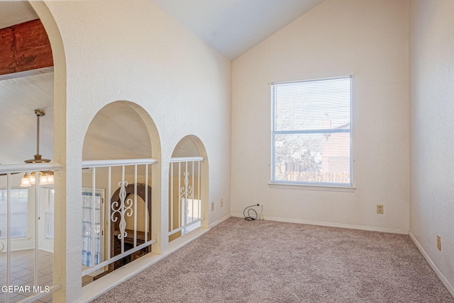 empty room with high vaulted ceiling, carpet flooring, and ceiling fan