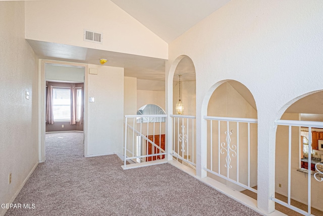 hall with carpet floors and high vaulted ceiling