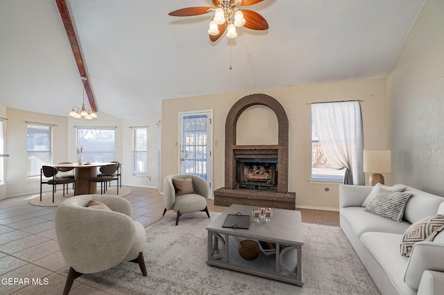 living room with lofted ceiling with beams, a brick fireplace, and a wealth of natural light