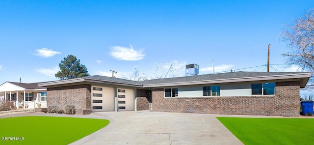 ranch-style house featuring a garage, a front lawn, and central air condition unit