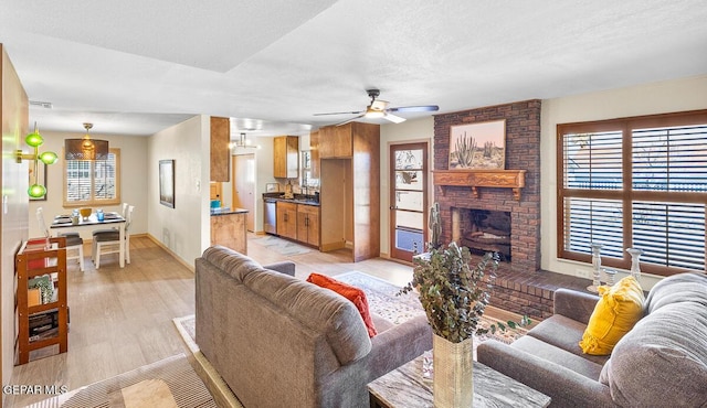 living room with ceiling fan, a textured ceiling, a fireplace, and light hardwood / wood-style floors